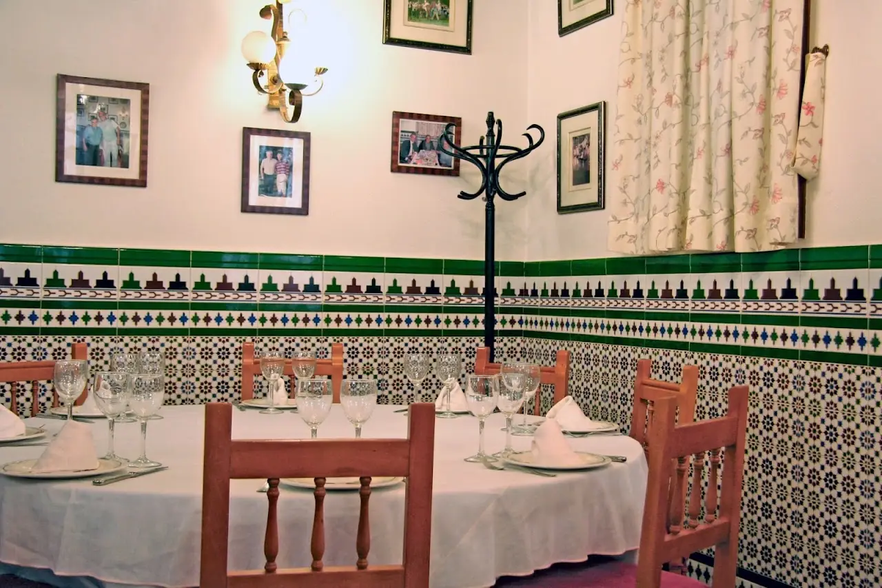 Dining room with tiled walls, framed pictures, and a table set with wine glasses.