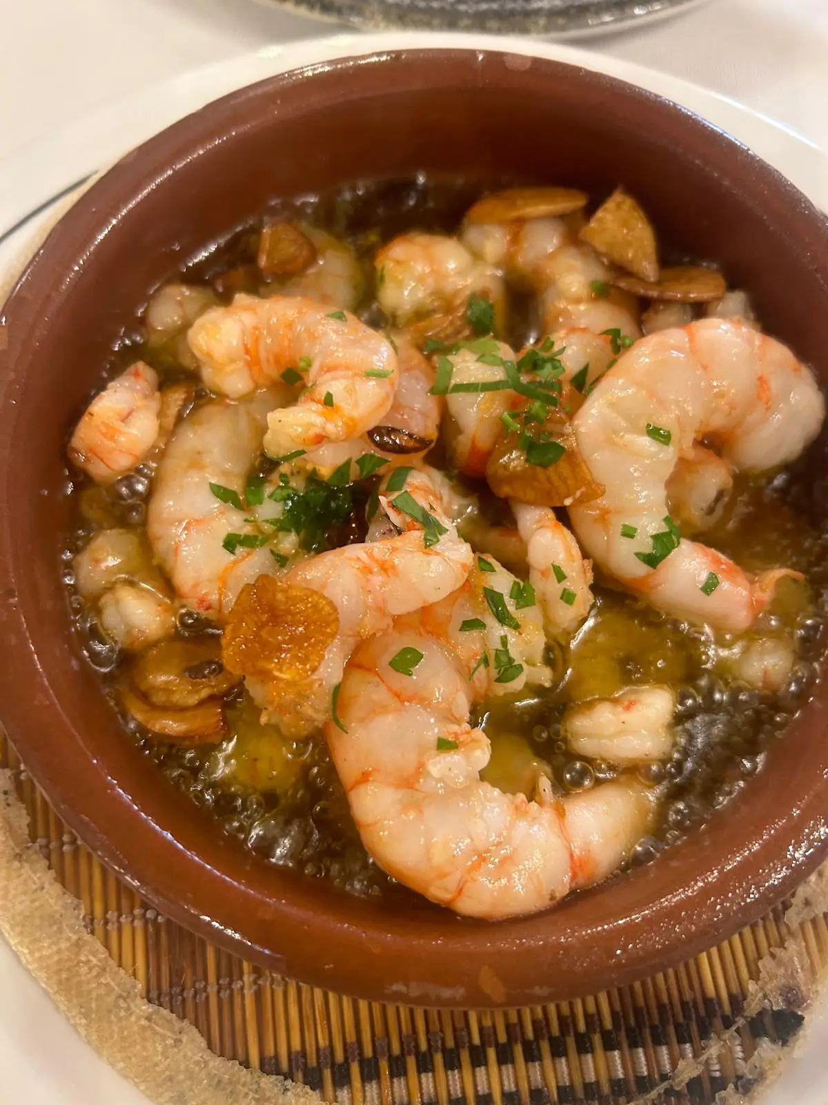 Garlic shrimp sizzling in a terracotta dish with parsley.