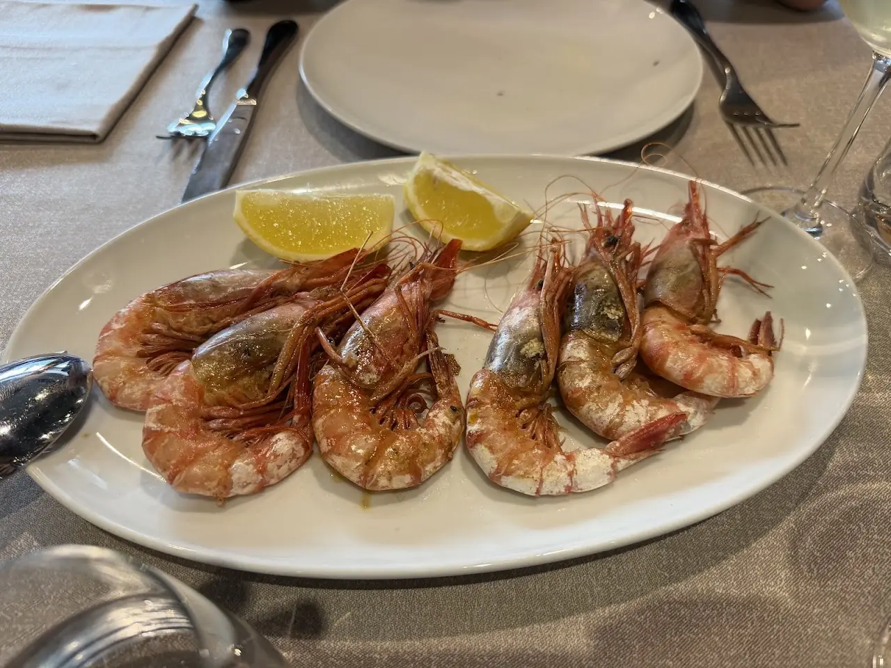 A plate of grilled whole prawns with lemon wedges