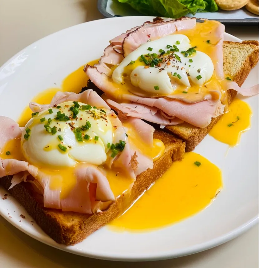 Two poached eggs and ham on toast, drizzled with hollandaise sauce