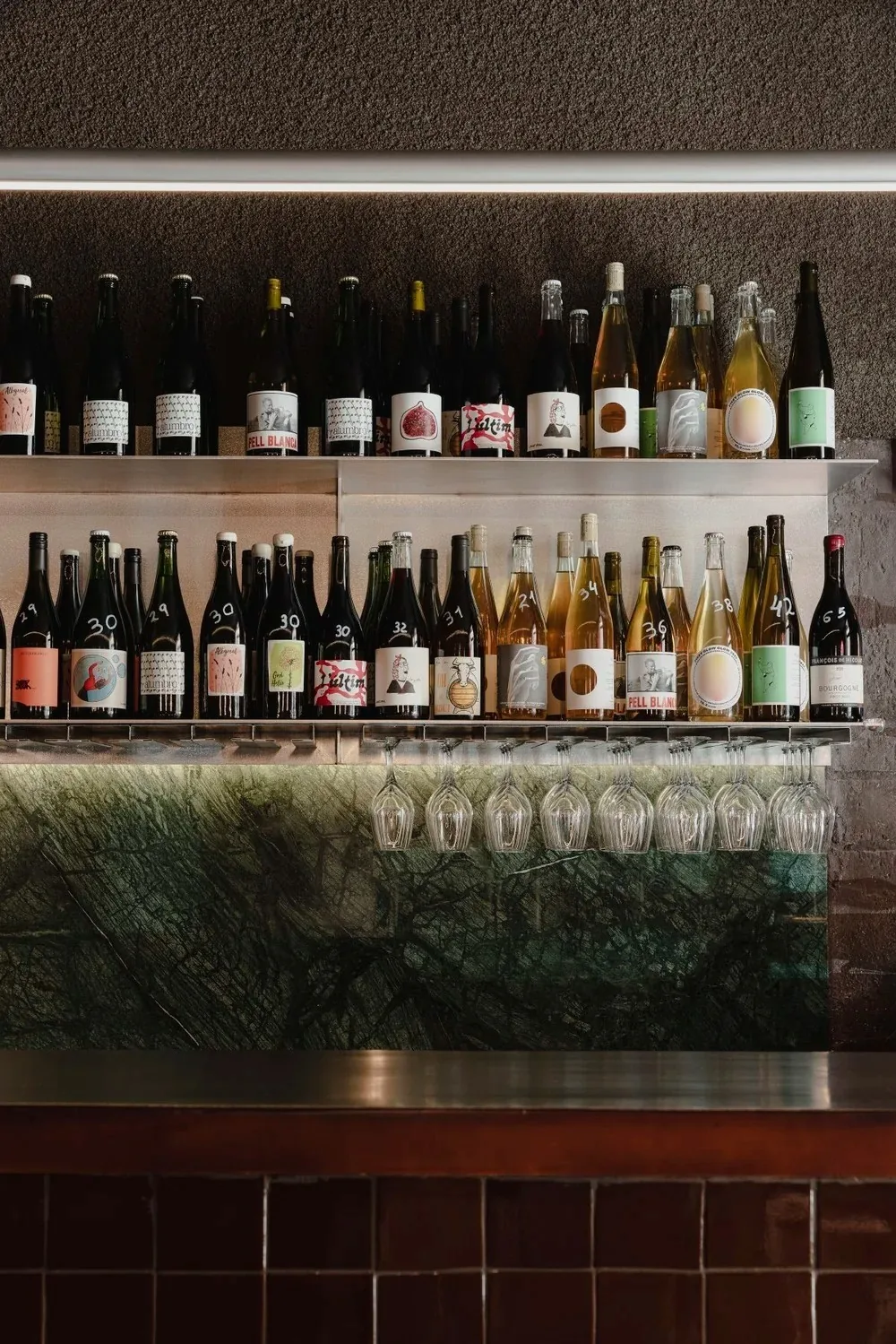 Shelves of wine bottles above a dark tiled bar counter