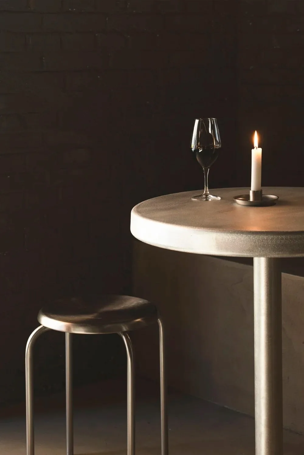 A small round table with a glass of wine and a lit candle