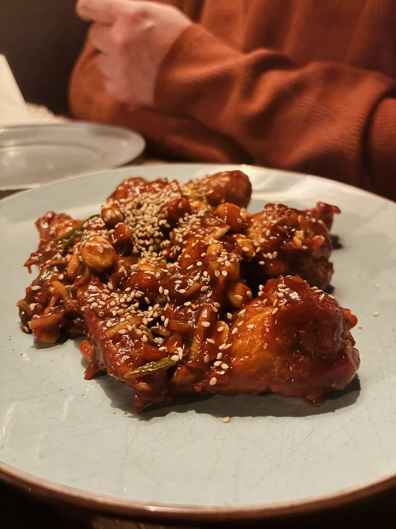 Glazed pieces of meat topped with sesame seeds on a white plate
