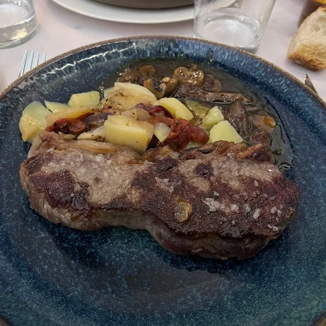 A grilled steak with roasted potatoes and mushrooms on a blue plate