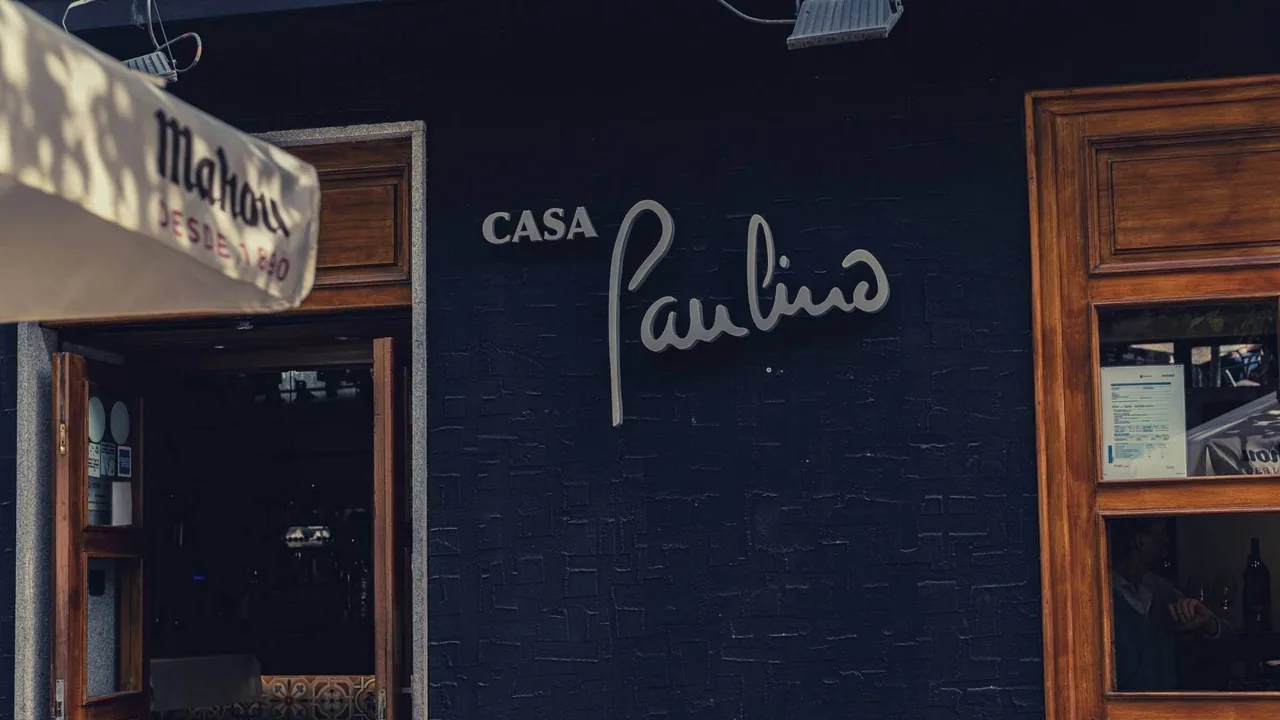 The dark blue front of a restaurant with a script sign above the entrance