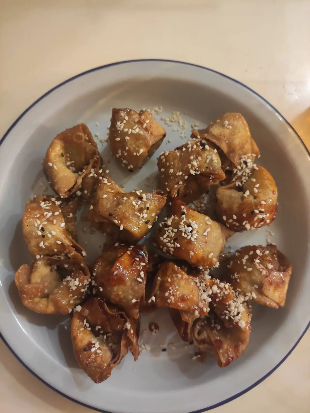 Sesame-topped fried dumplings on a blue-rimmed plate.