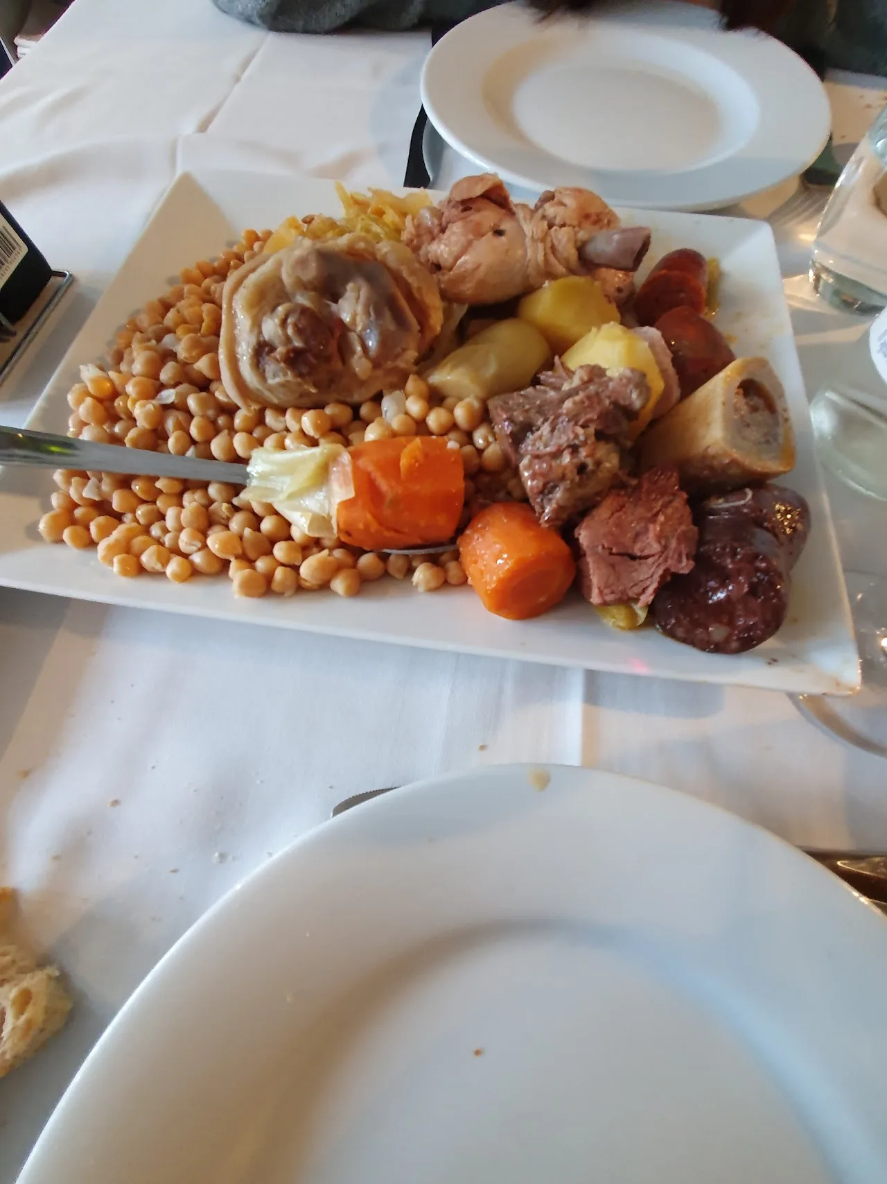 A platter of cocido madrileno with garbanzo beans, meats, and vegetables