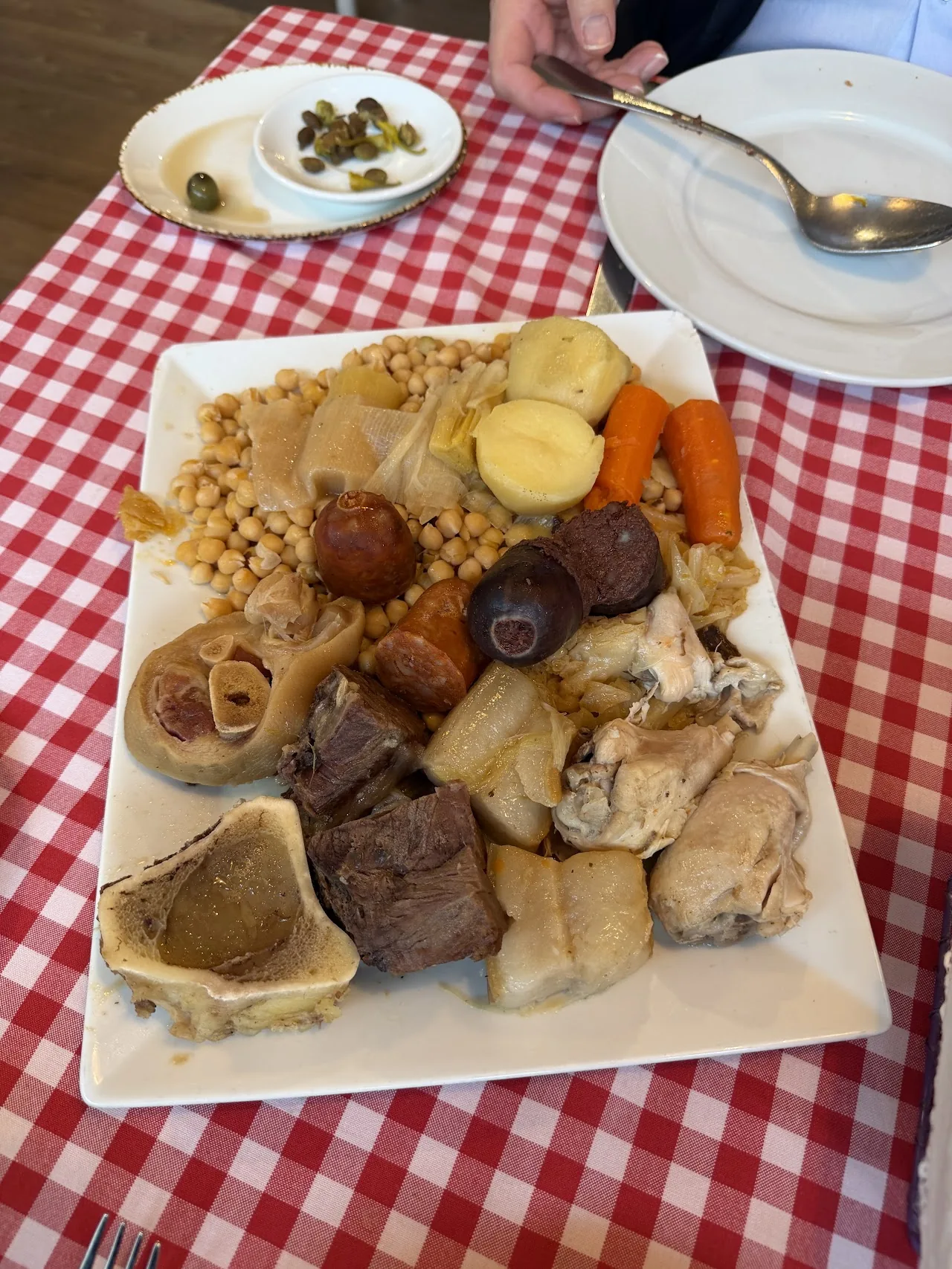 A close-up of cocido madrileno with chickpeas, sausage, and boiled vegetables