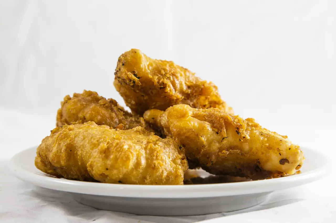 Battered fried fish pieces stacked on a white plate