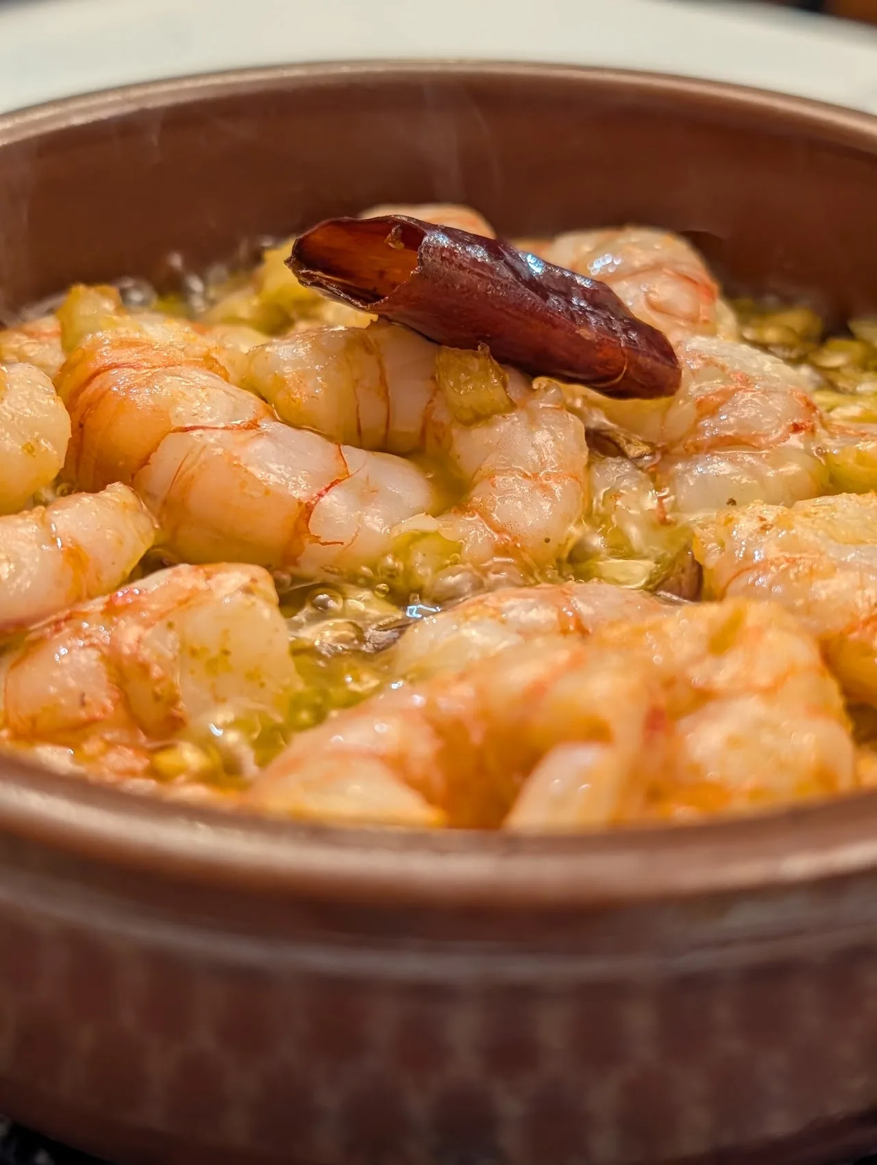 Sizzling garlic shrimp (gambas al ajillo) in a clay dish