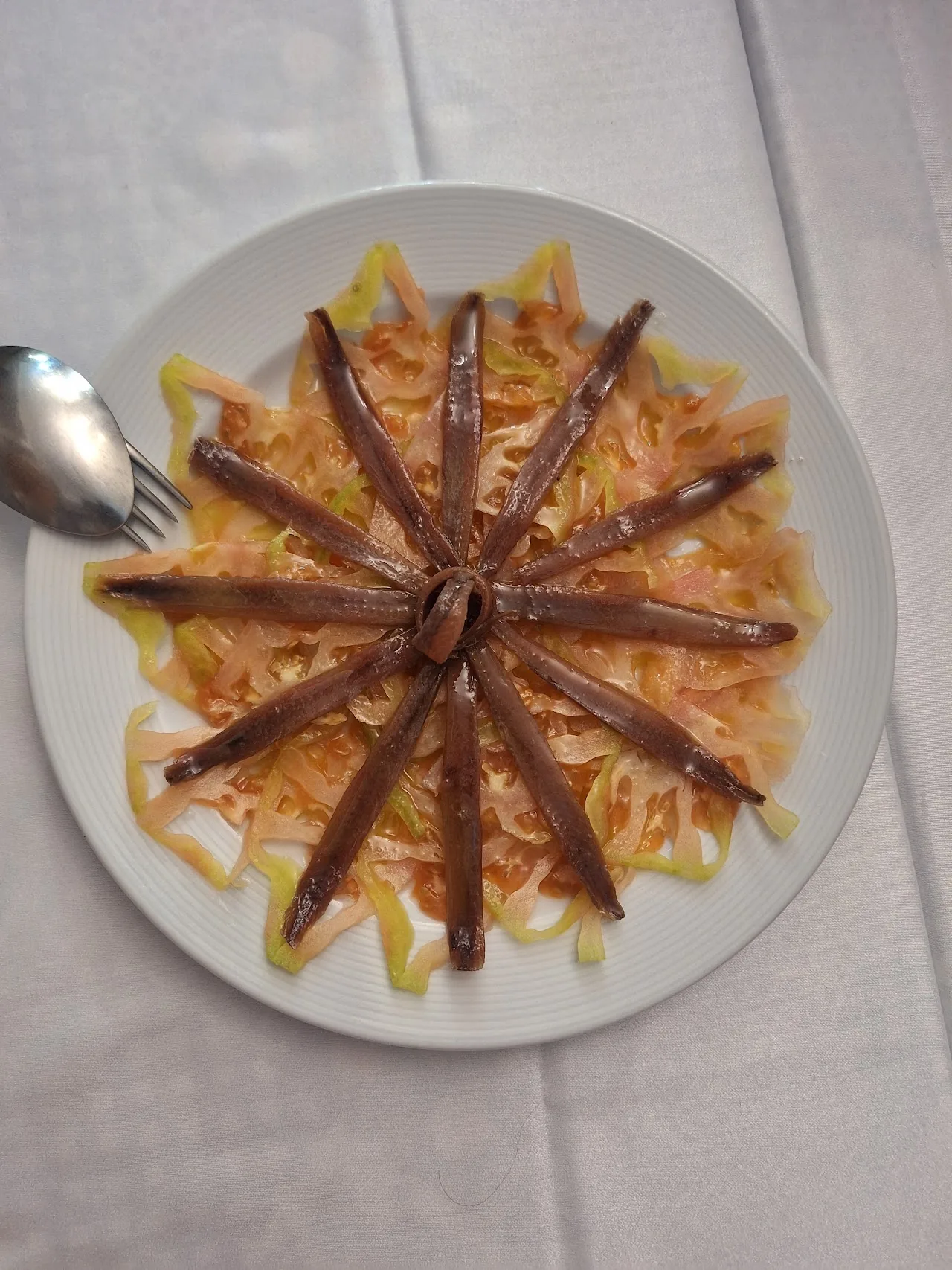 Grilled sardines arranged in a fan pattern on a plate