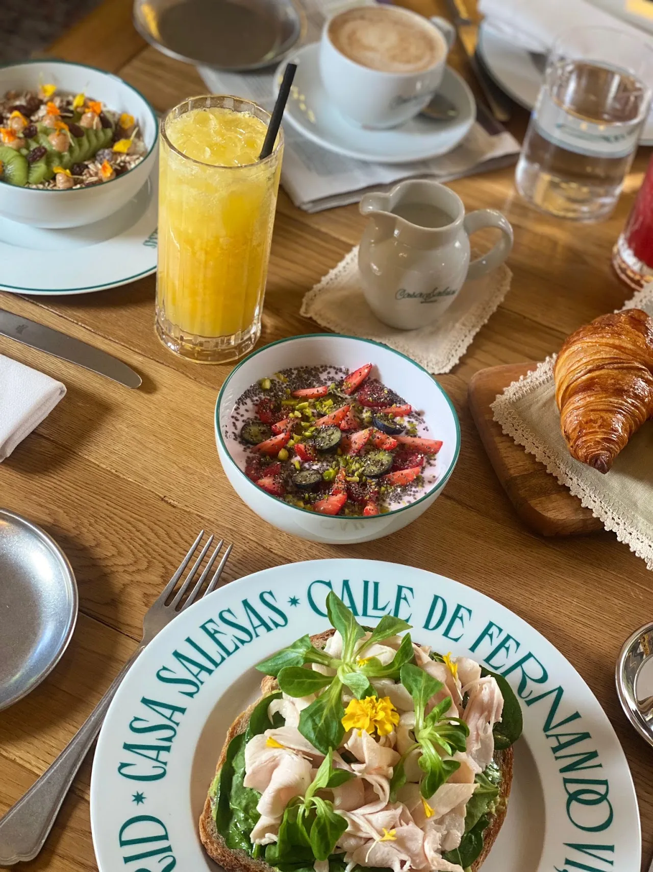 A breakfast spread with a salad, orange juice, croissant, and coffee, seen from above
