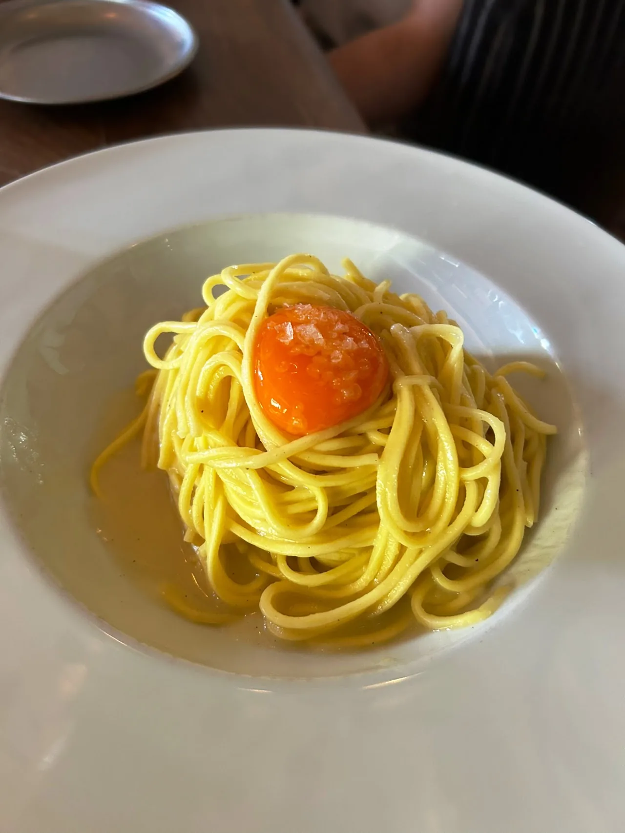 A plate of spaghetti topped with a raw egg yolk