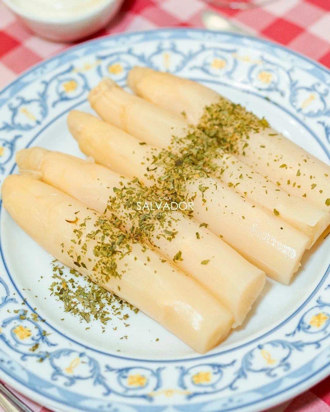 White asparagus spears on a decorated plate with a sprinkle of herbs