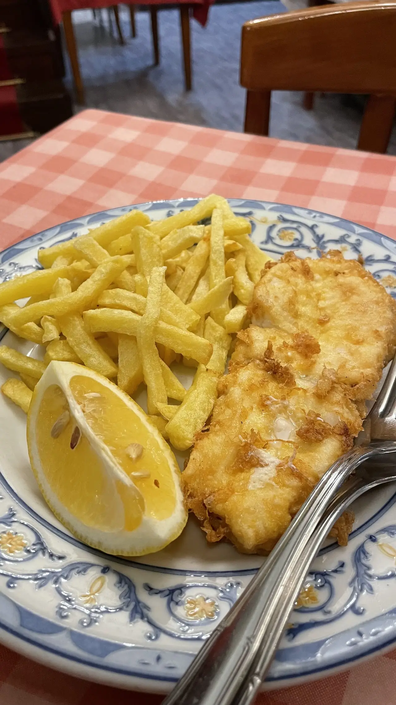 Fried fish fillet with french fries and a lemon wedge.