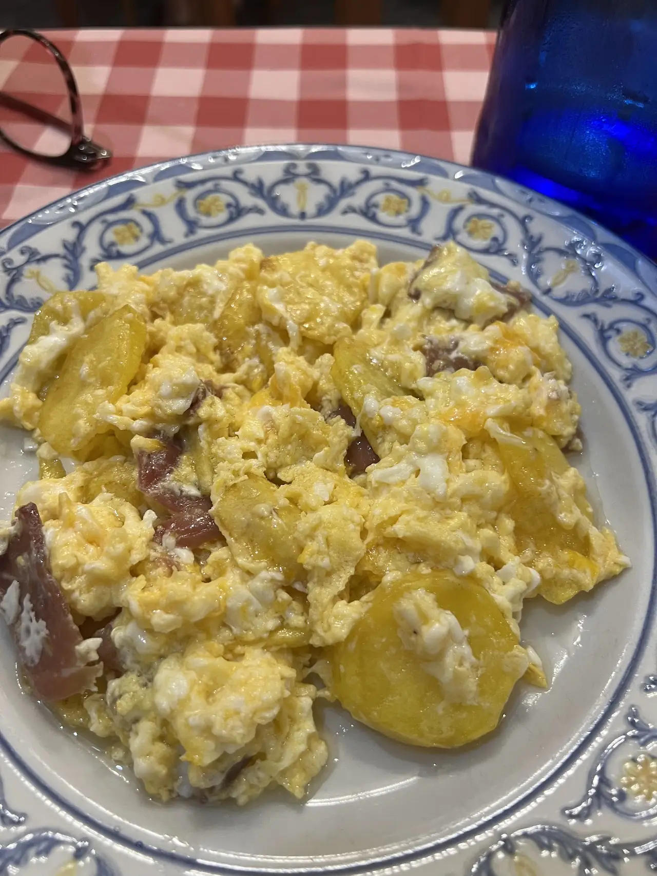Scrambled eggs with sliced potatoes on a decorative plate.