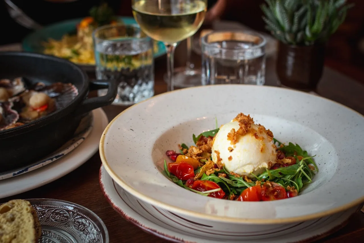 A ball of burrata cheese on a bed of arugula and cherry tomatoes