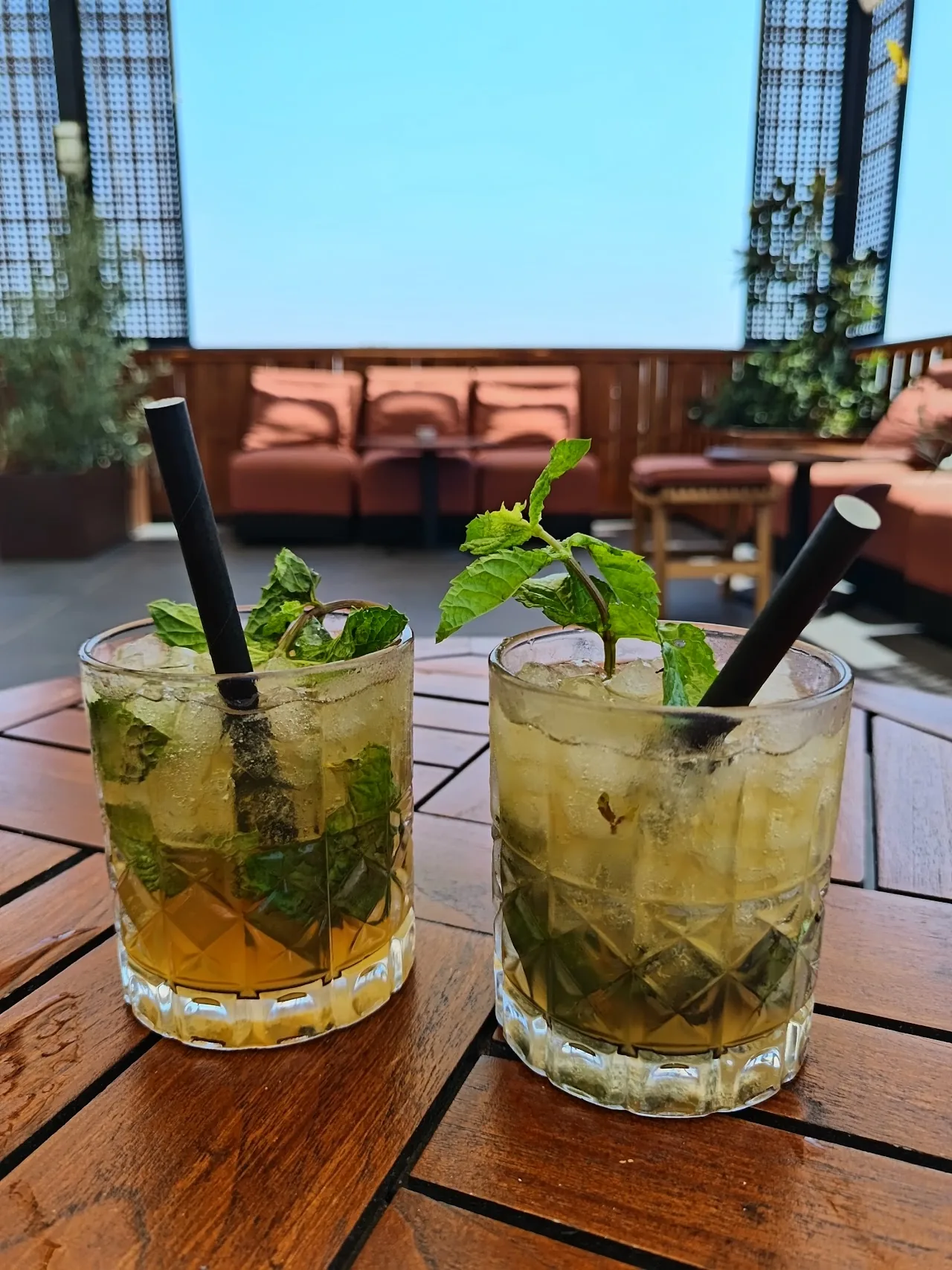 Two mojito cocktails with mint garnish on a wooden table