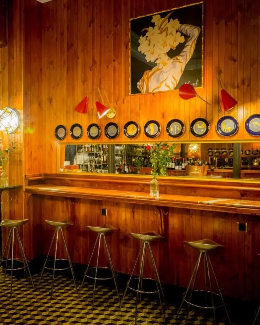 The venue's empty wood-paneled bar counter with stools, wall plates, and lamps