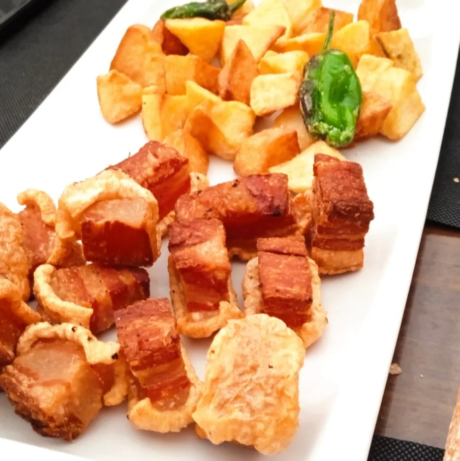 Crispy fried pork belly bites (torreznos) with a slice of jalapeno