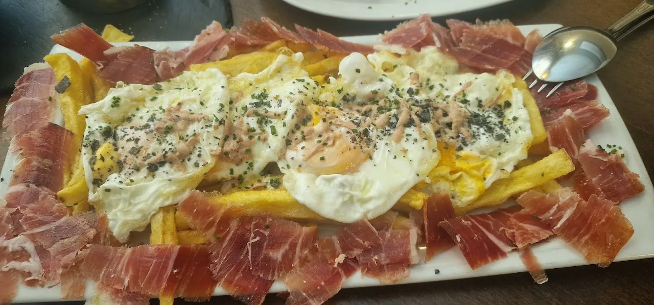Huevos rotos: fried eggs over ham and shoestring fries on a platter