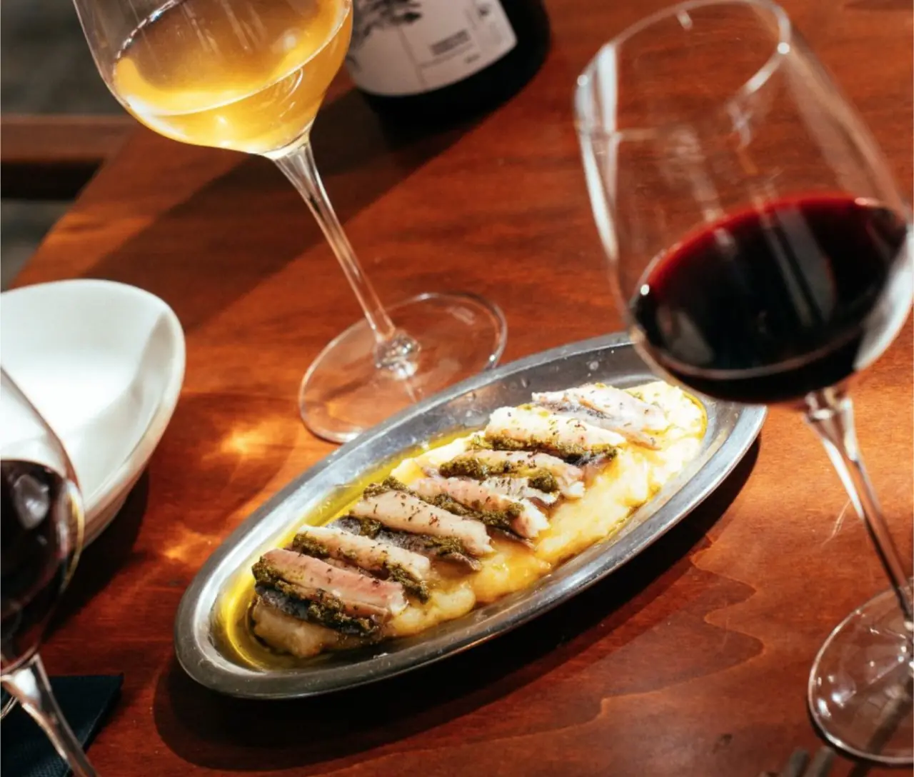 Grilled fish fillets with green herb sauce over a puree, plated on an oval metal dish, Casa Xica