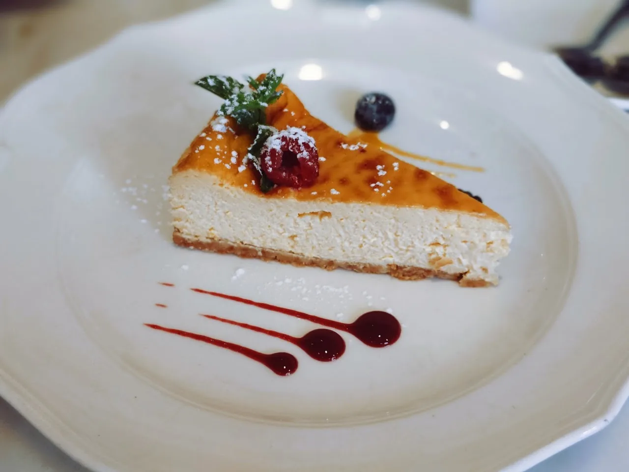 A slice of cheesecake with berry garnish and fruit coulis
