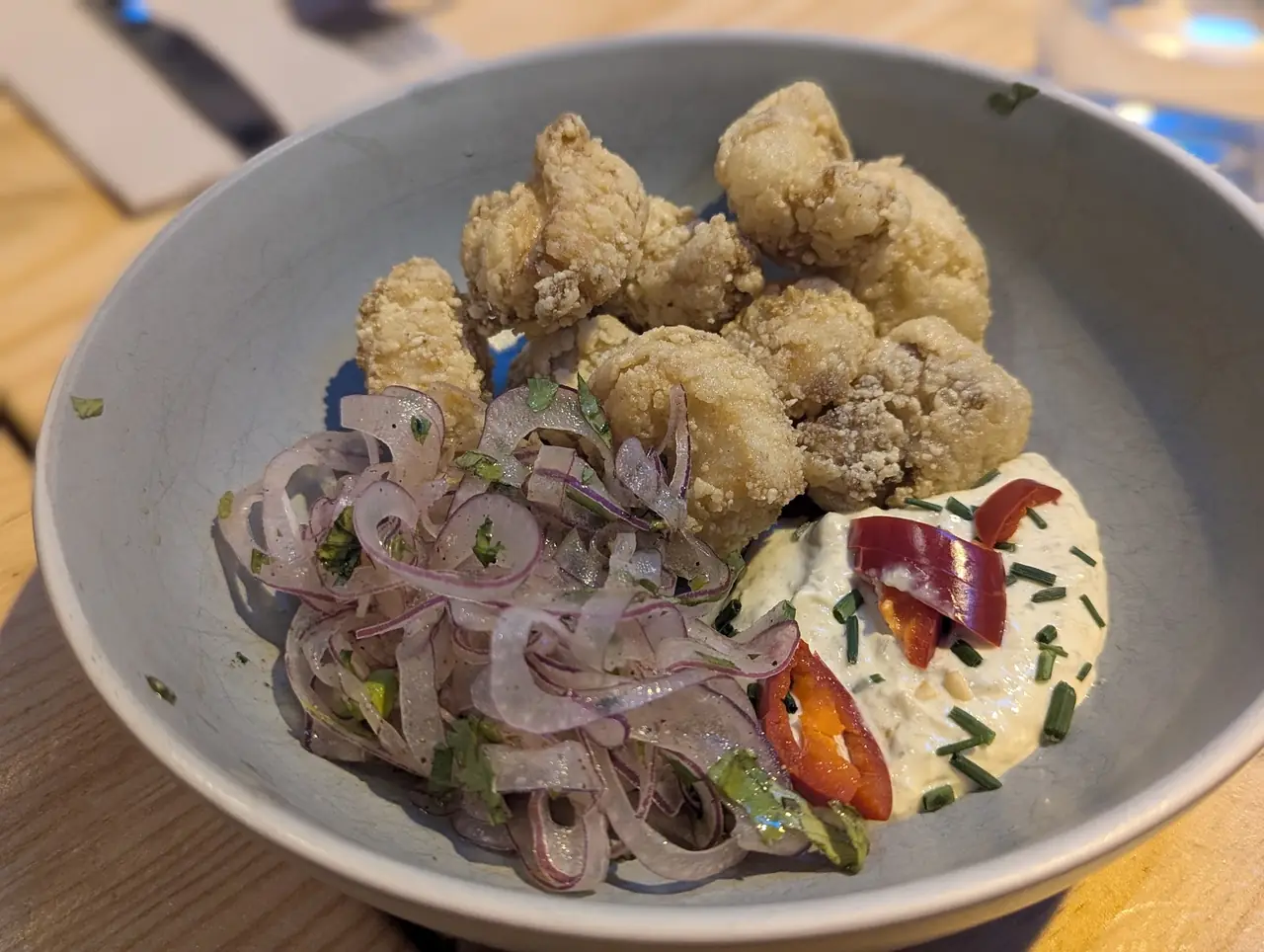 Crispy fried calamari with pickled red onion, chili and a creamy sauce in a bowl
