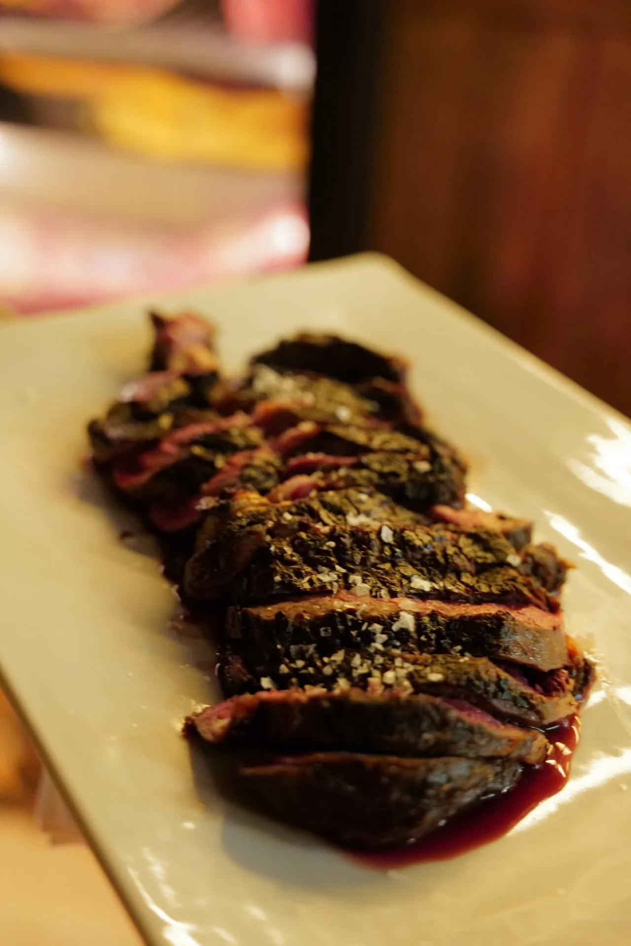Thin slices of grilled steak on a white rectangular plate