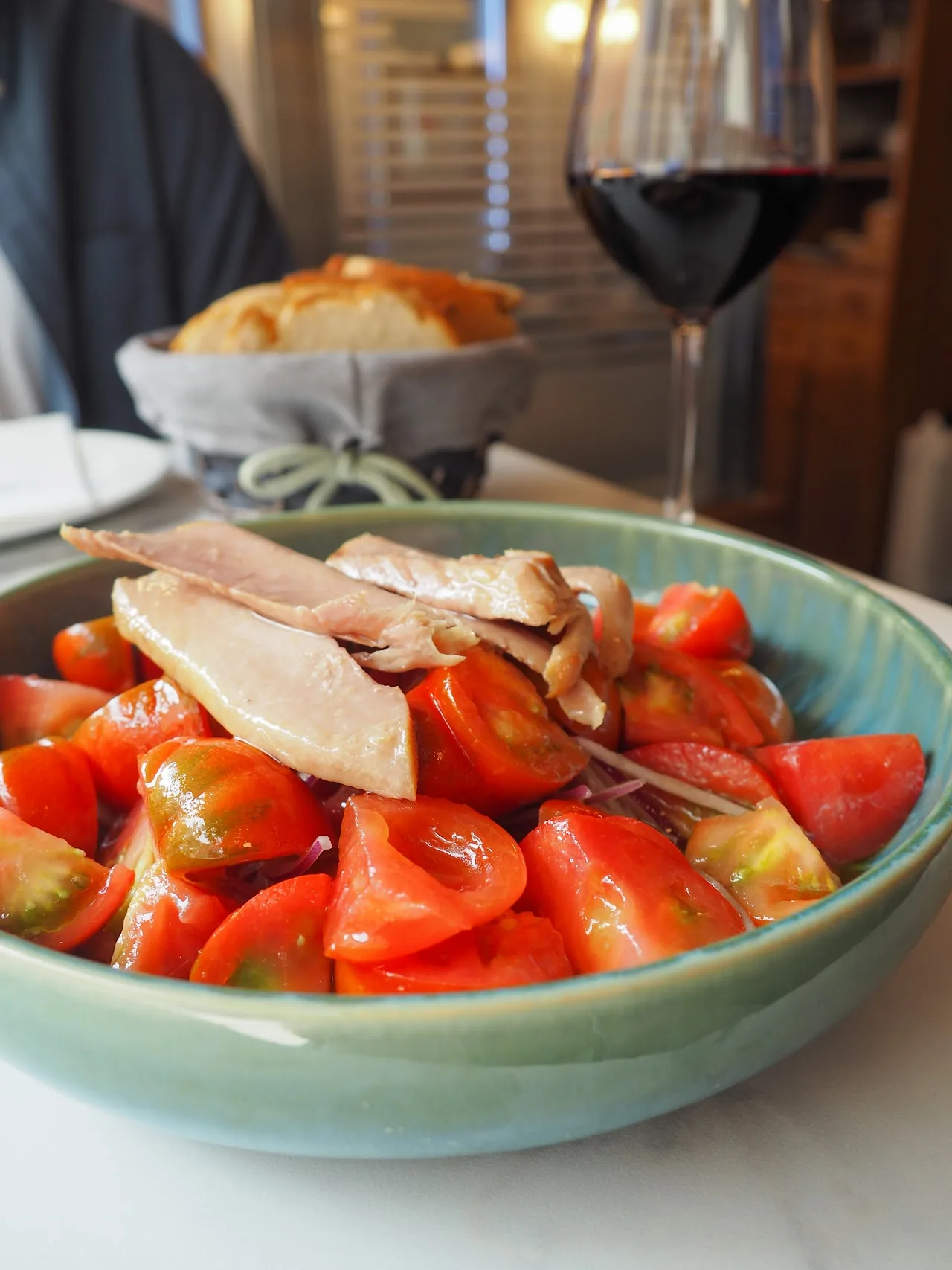 A bowl of sliced tomato salad topped with anchovy fillets