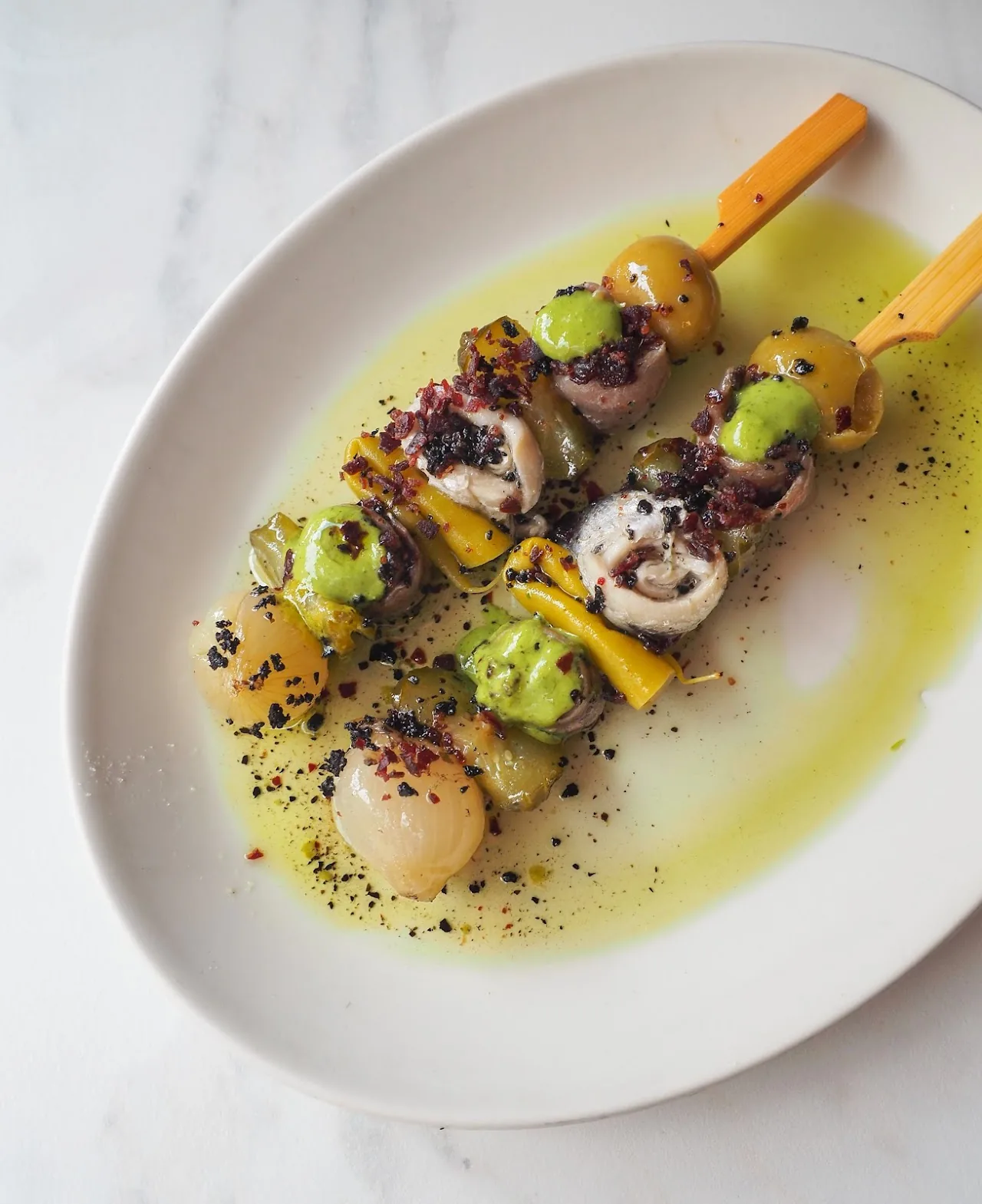 Grilled octopus and potato skewers with a green sauce
