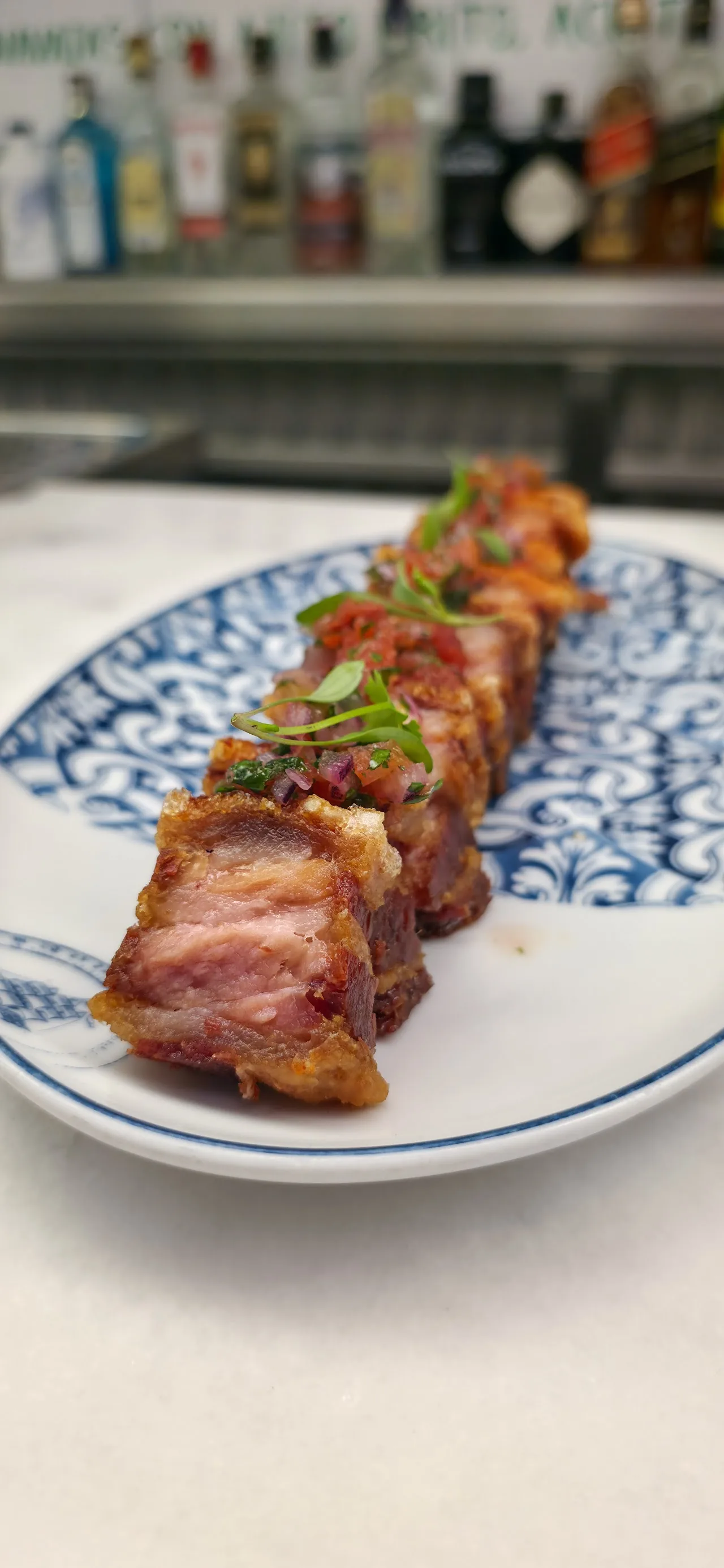 A grilled meat skewer served on a patterned plate