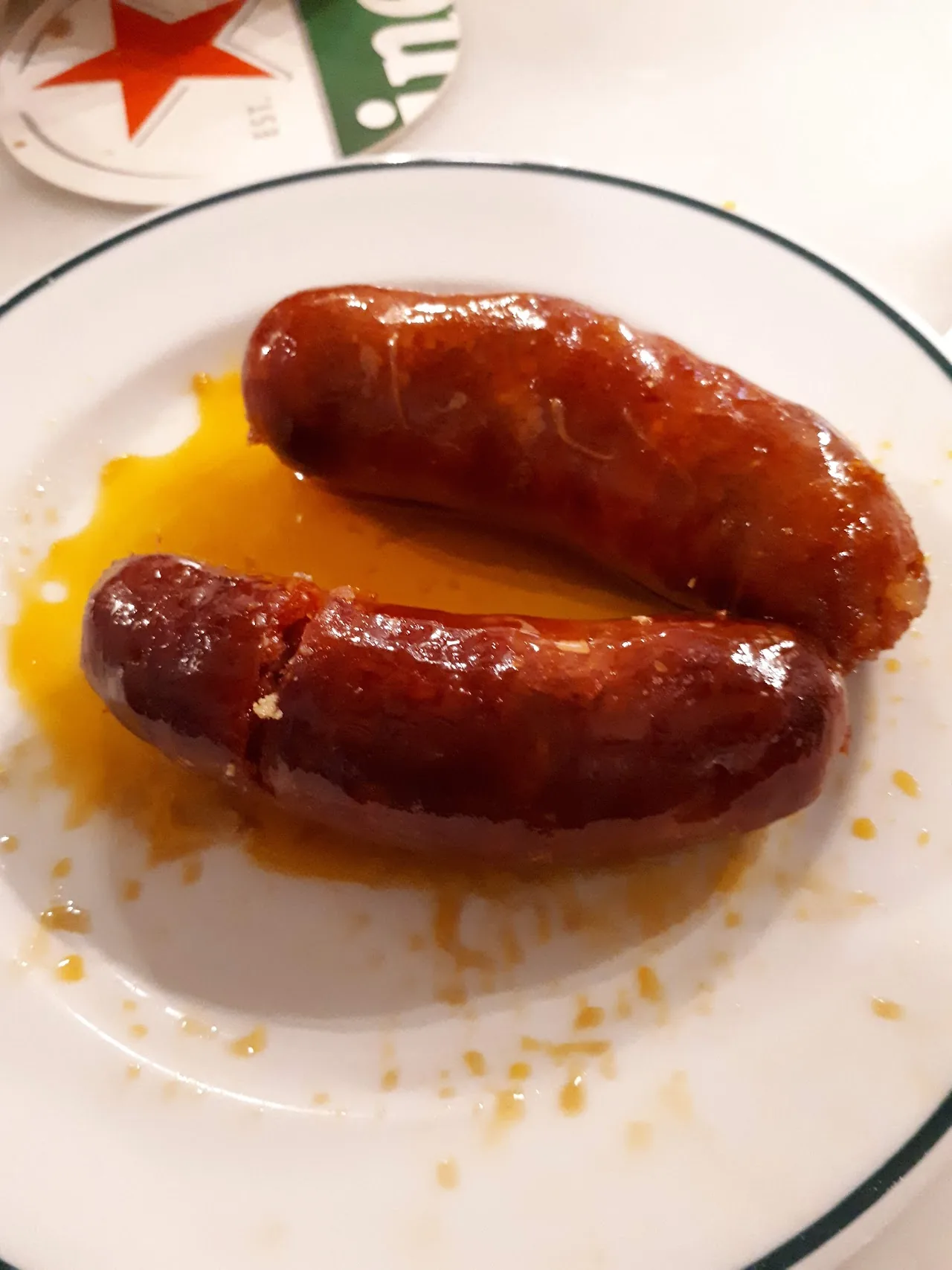 Two grilled chorizo sausages in their own juices on a plate