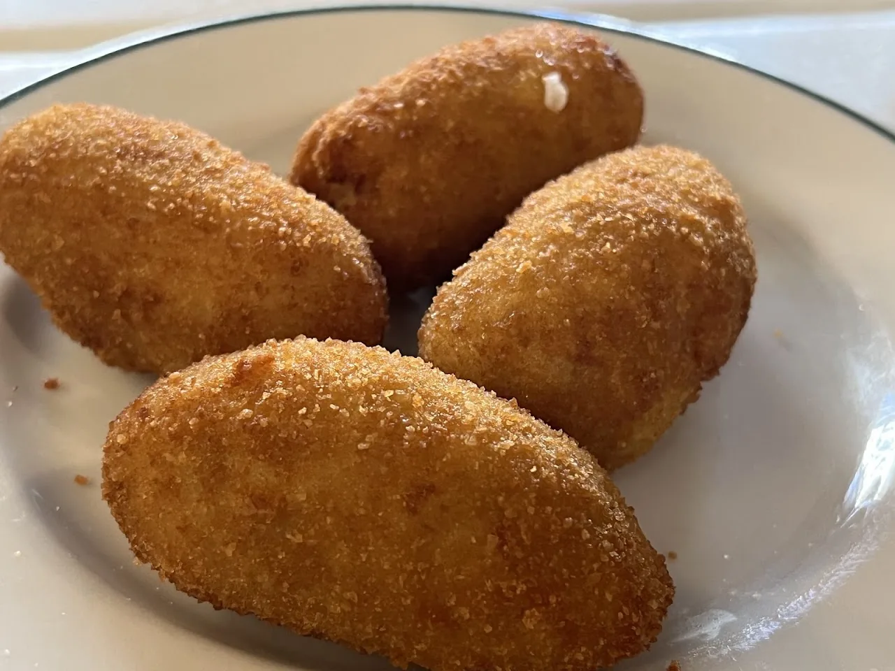 Four golden fried croquettes on a plate