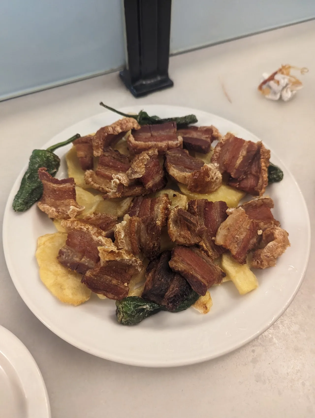 Chunks of pork or beef with grilled padron peppers on a bed of potatoes