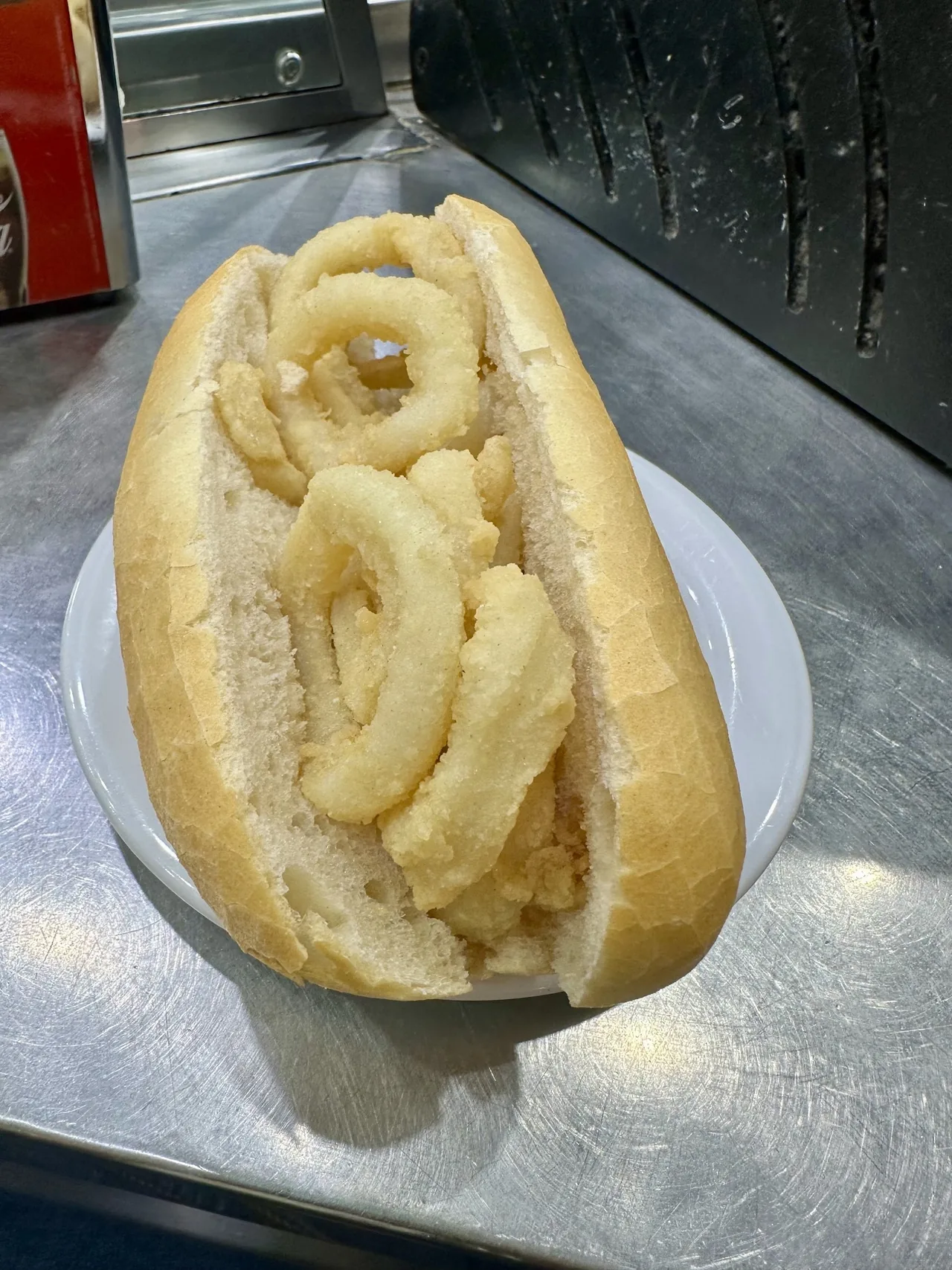 A long roll filled with fried squid rings on a white plate