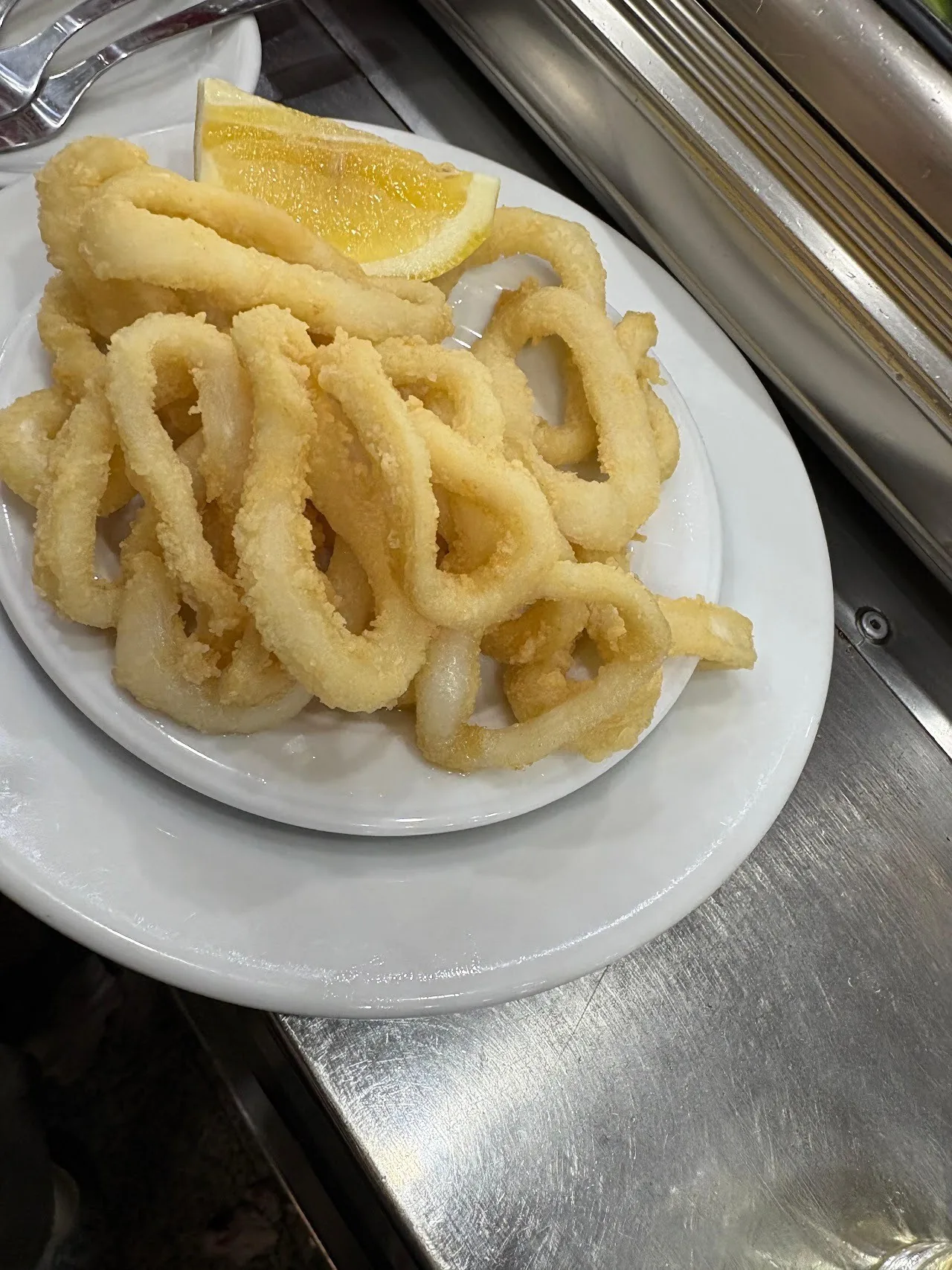 A plate of fried squid rings with a lemon wedge
