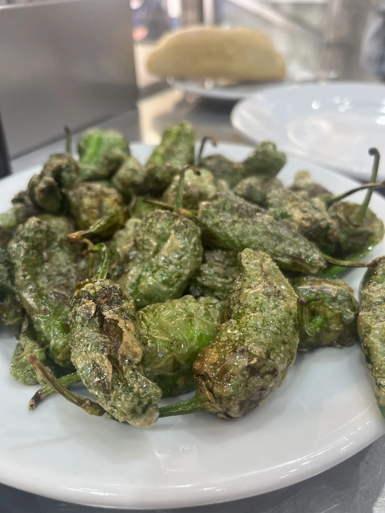 A plate of fried padron peppers with a lemon wedge
