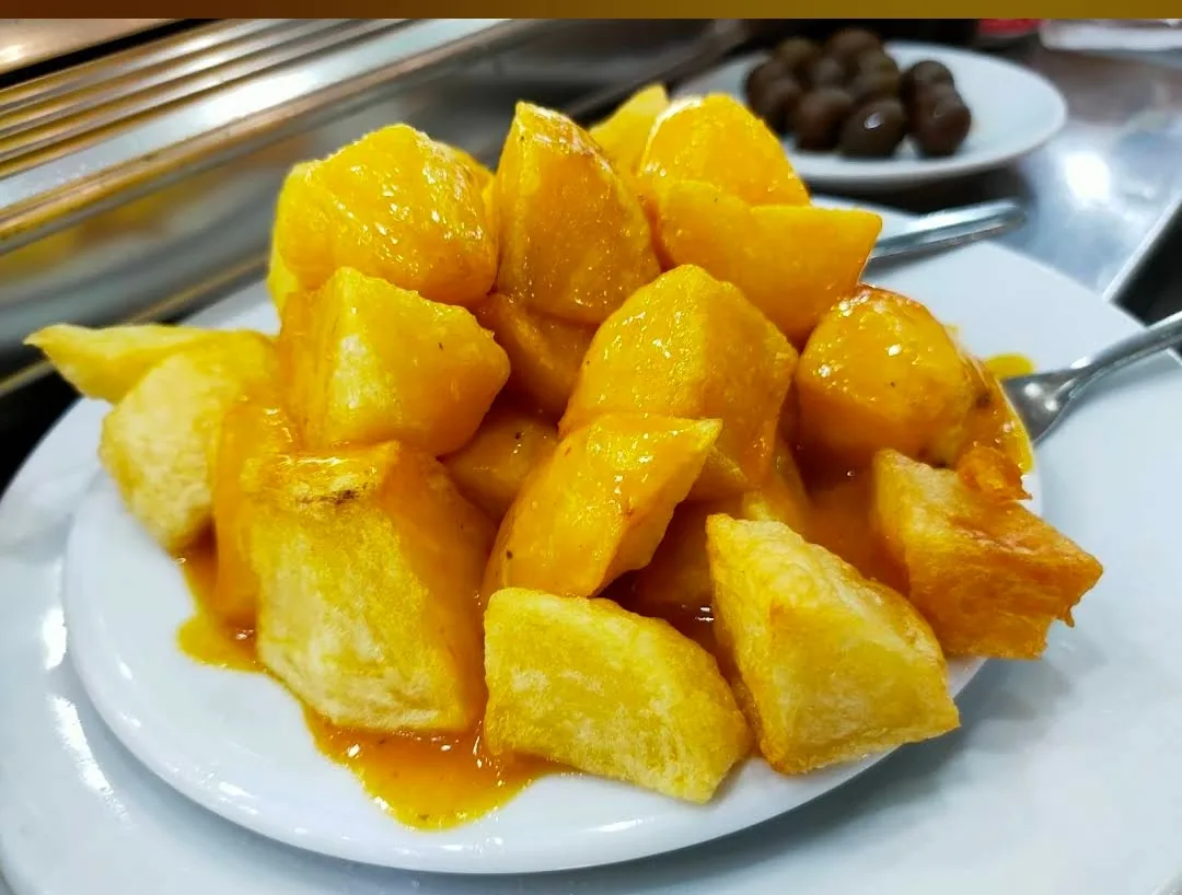 A plate of patatas bravas drizzled in spicy sauce