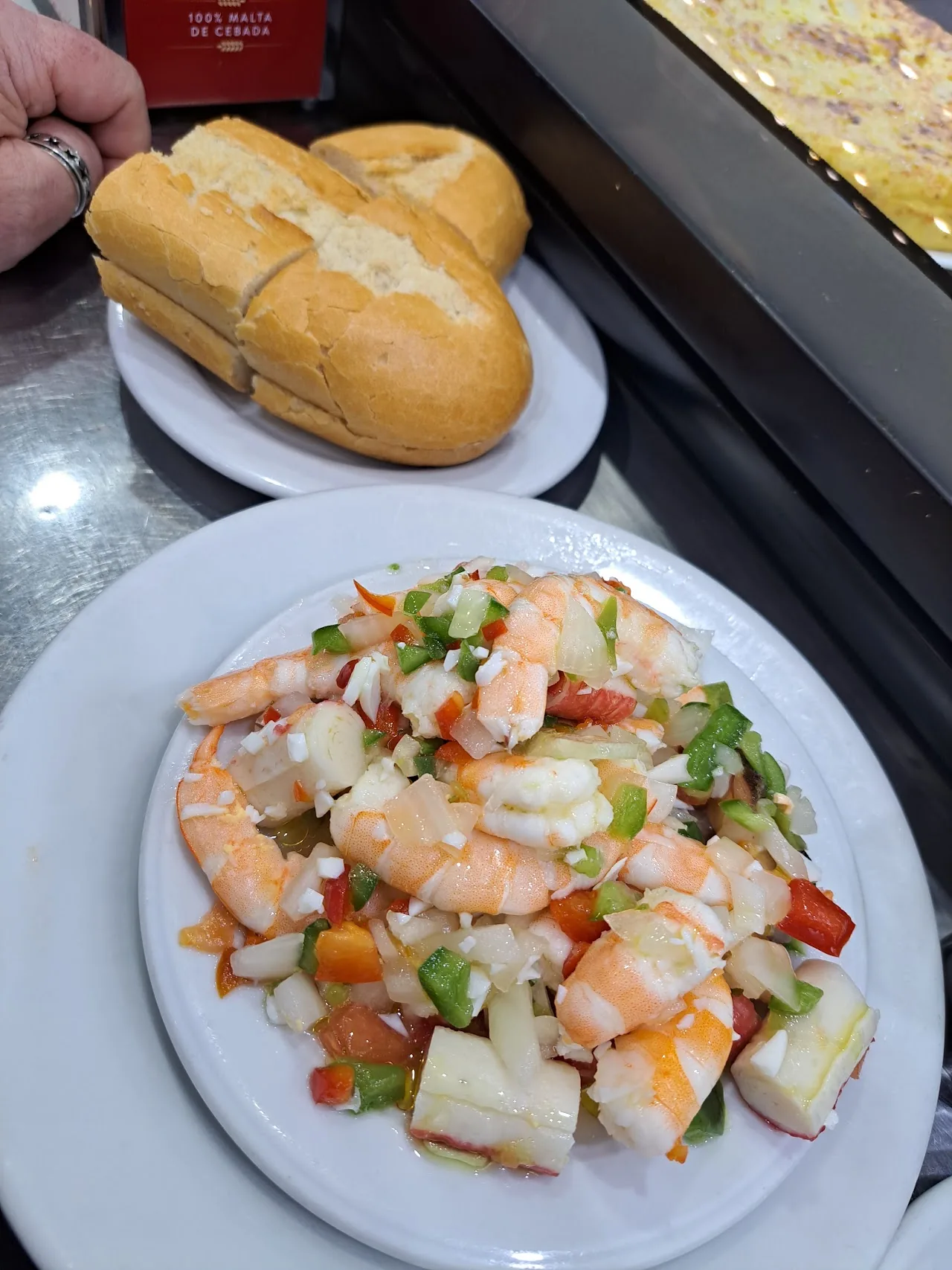 A plate of shrimp and vegetable salad next to a piece of bread