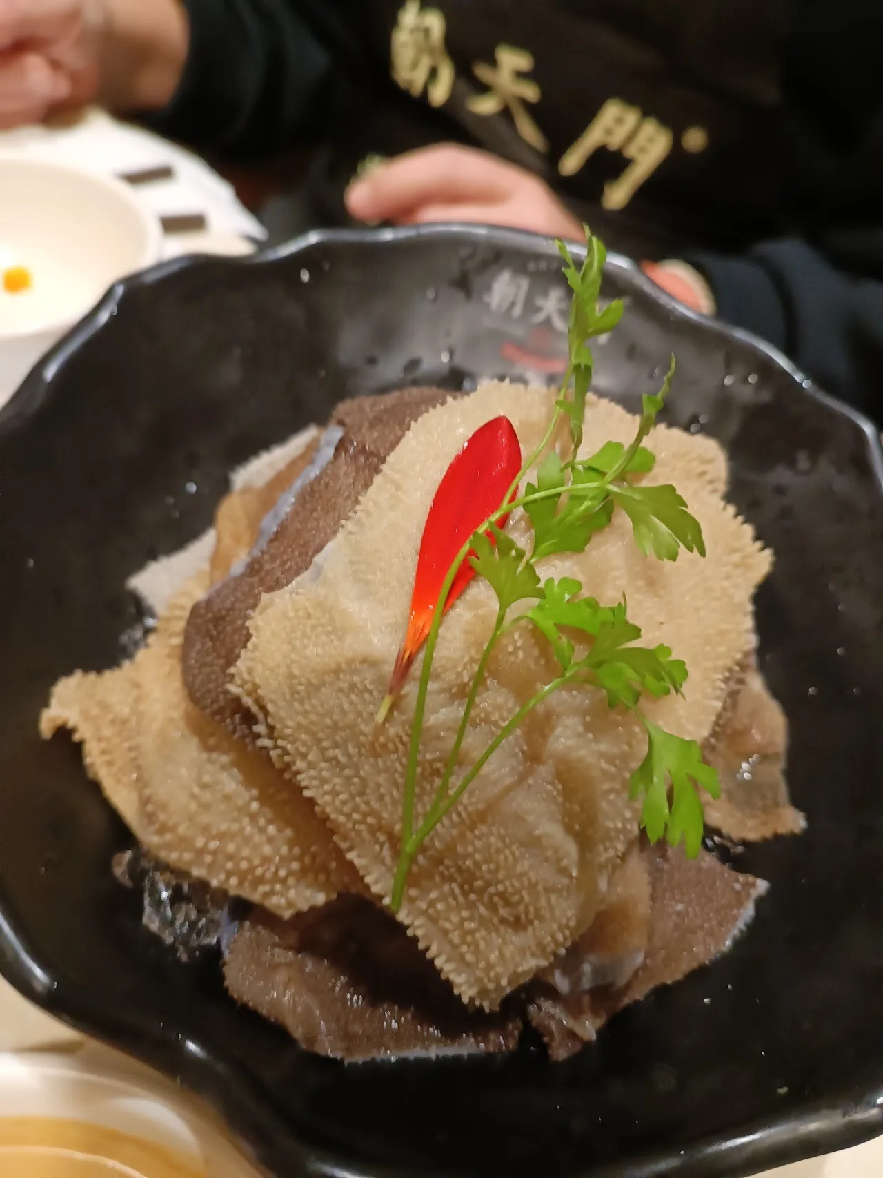 Sliced tripe in a black bowl with a chilli garnish