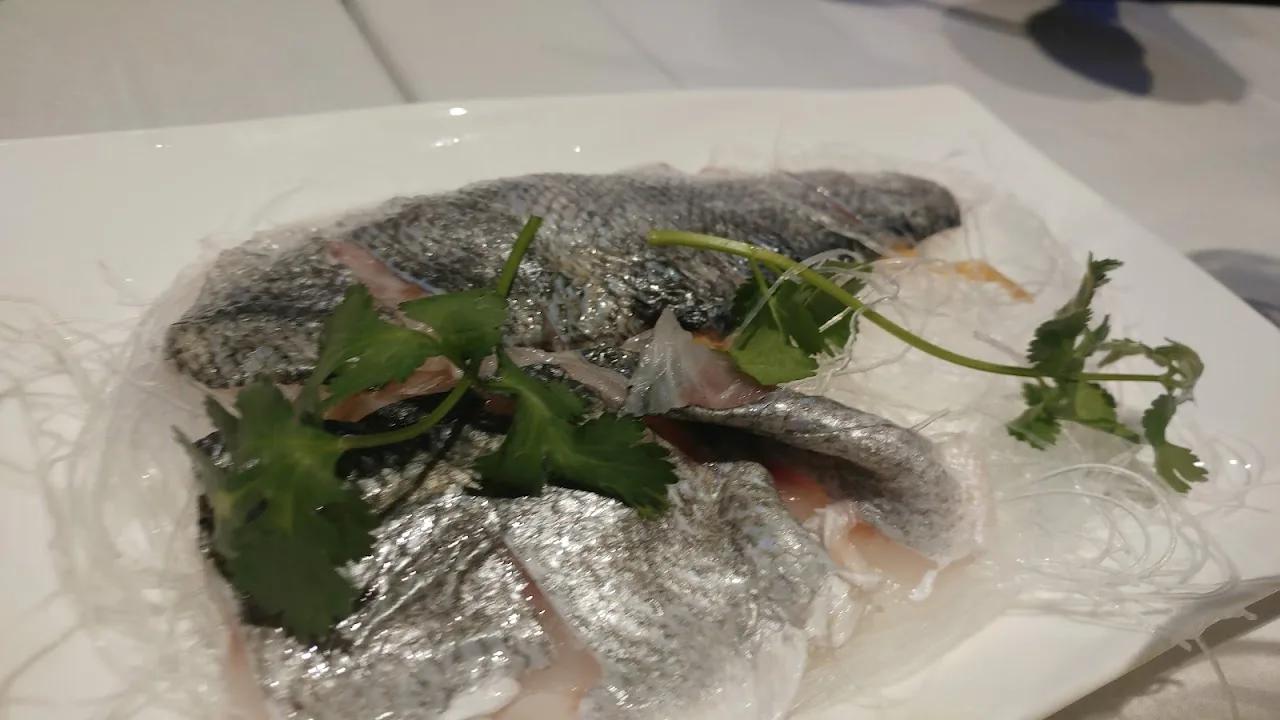 A whole steamed fish garnished with herbs