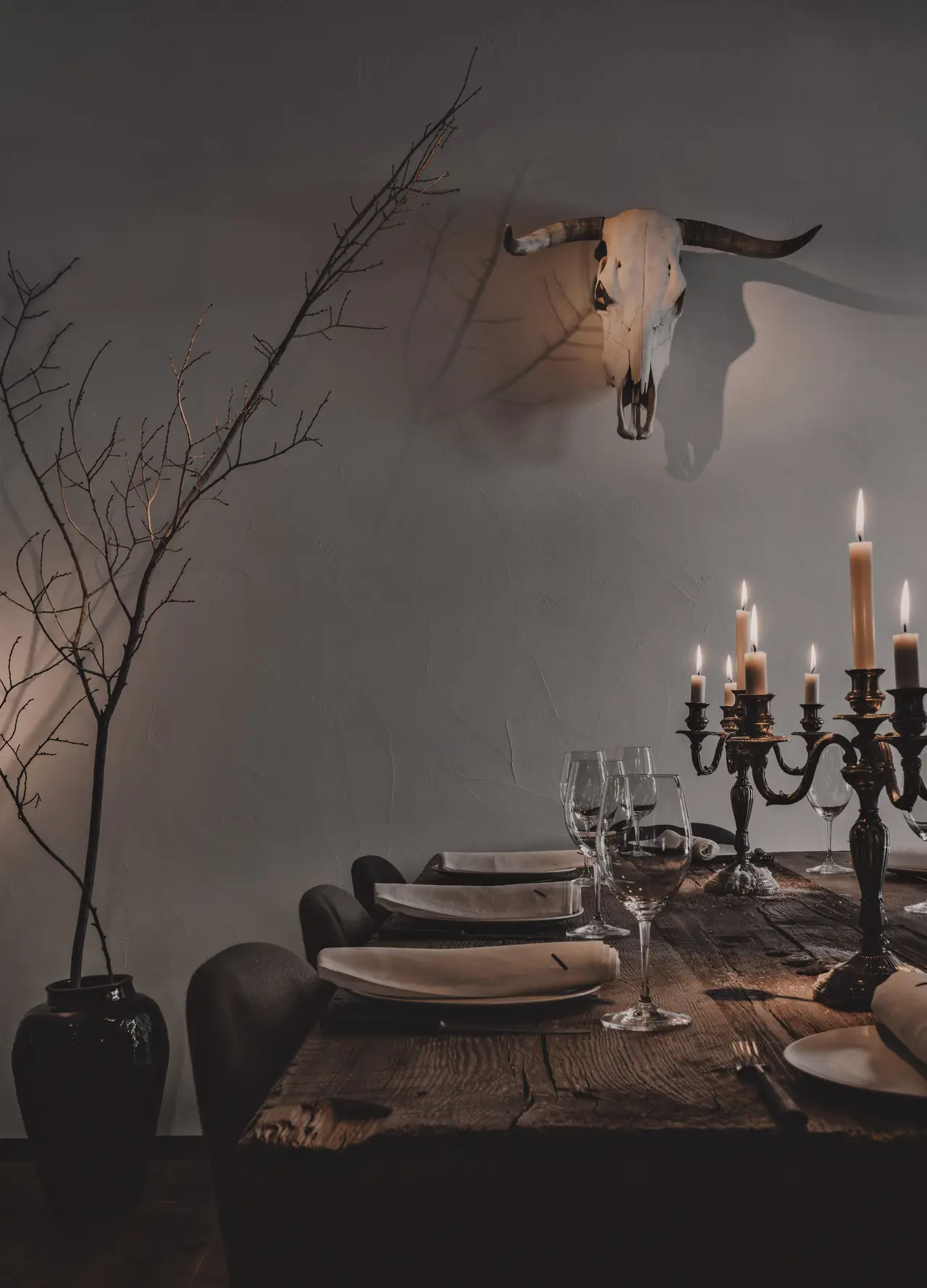 Candlelit dining room at Charrúa with set tables, wine glasses, and a bull skull mounted on the wall