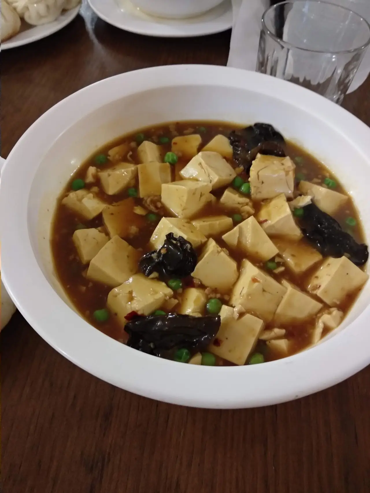 Mapo tofu with cubed tofu in a spiced sauce on a white plate, at Chen Ji.