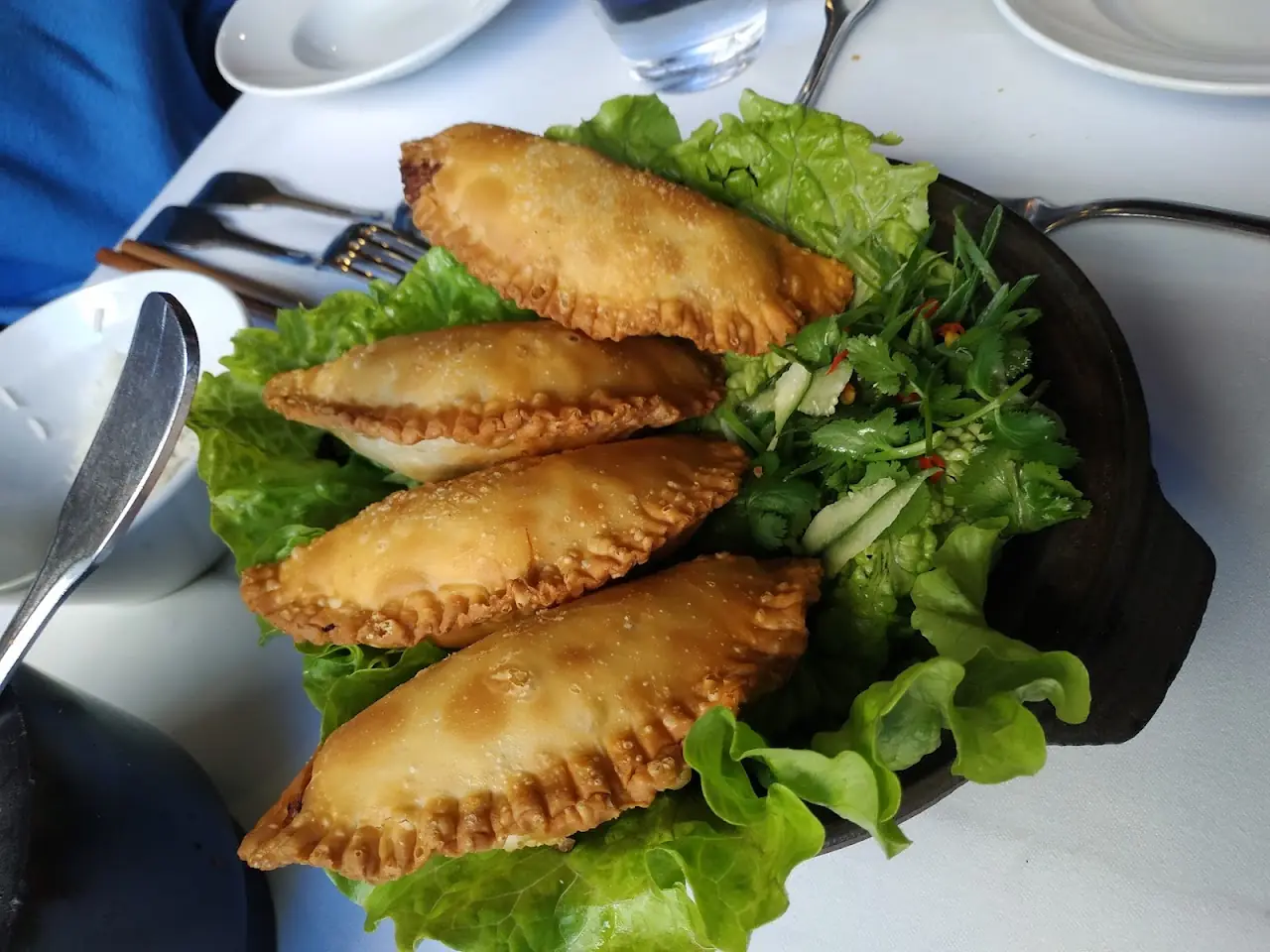 Golden fried empanadas on a bed of lettuce leaves