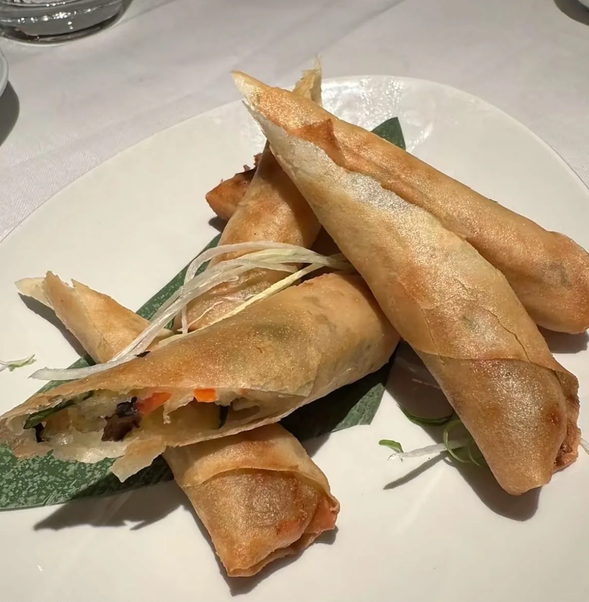 Crisp golden spring rolls cut open to show the vegetable filling