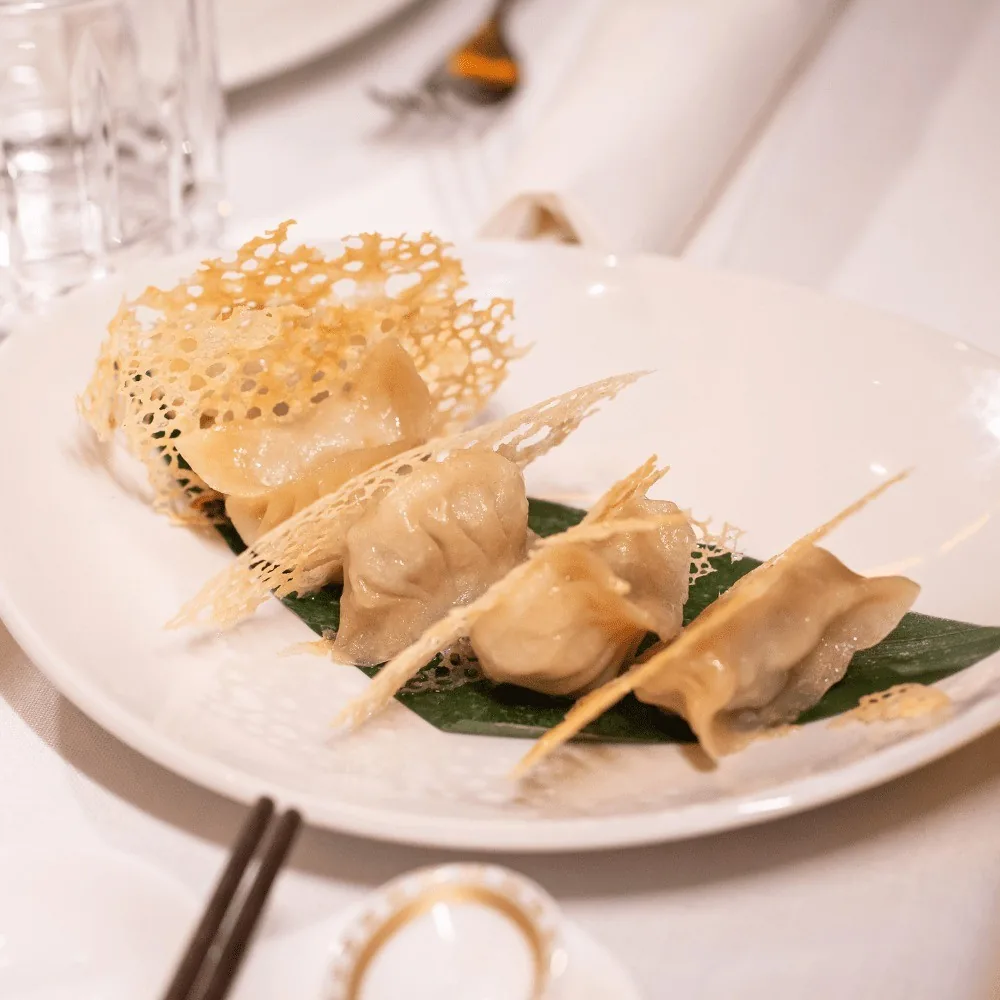 Pan-fried dumplings on a white plate with a crisp lattice