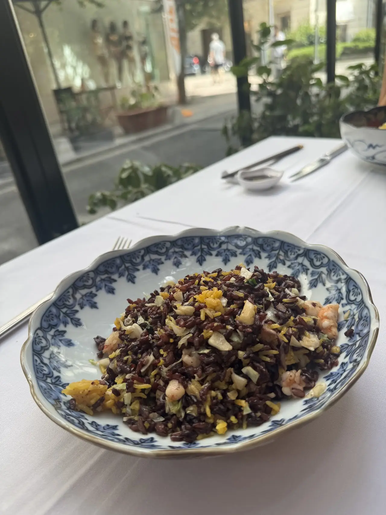 A serving of fried rice with vegetables in a decorative blue and white bowl.