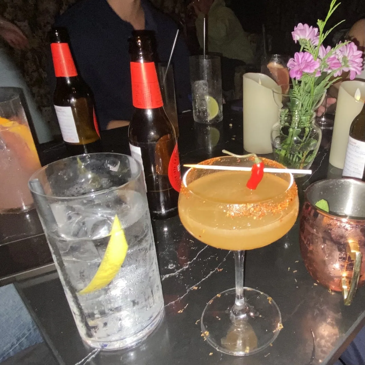 A gin and tonic and an orange cocktail on a bar table