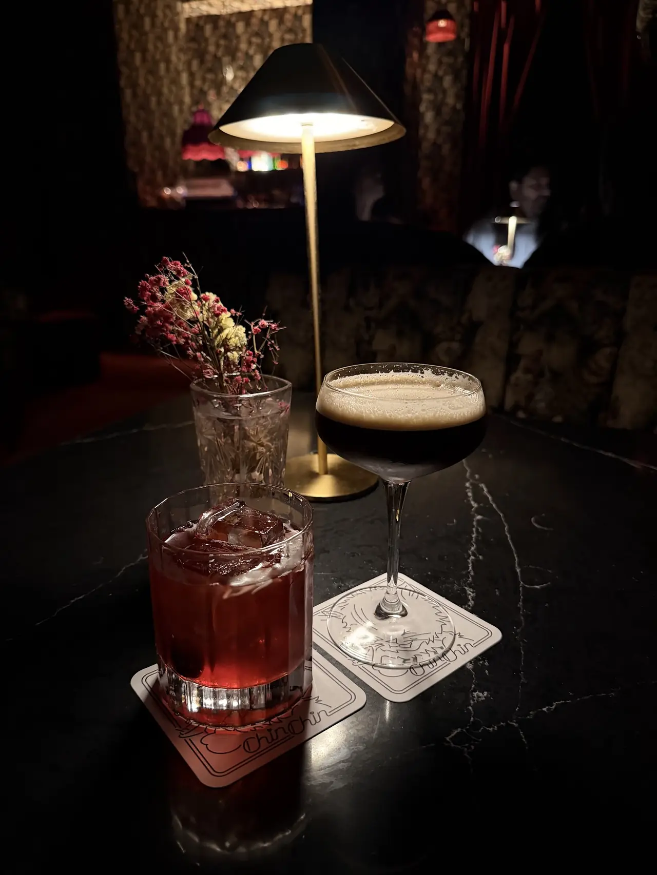 Two cocktails viewed from above, one garnished with citrus